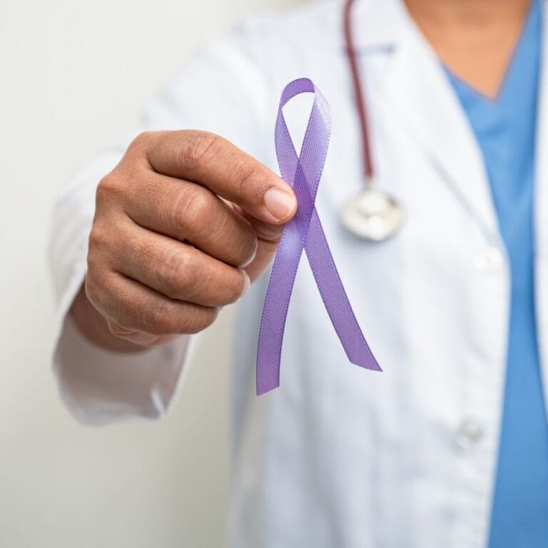 Zdjęcie przedstawia lekarza trzymającego fioletową wstążkę - symbol profilaktyki nowotworów jąder.